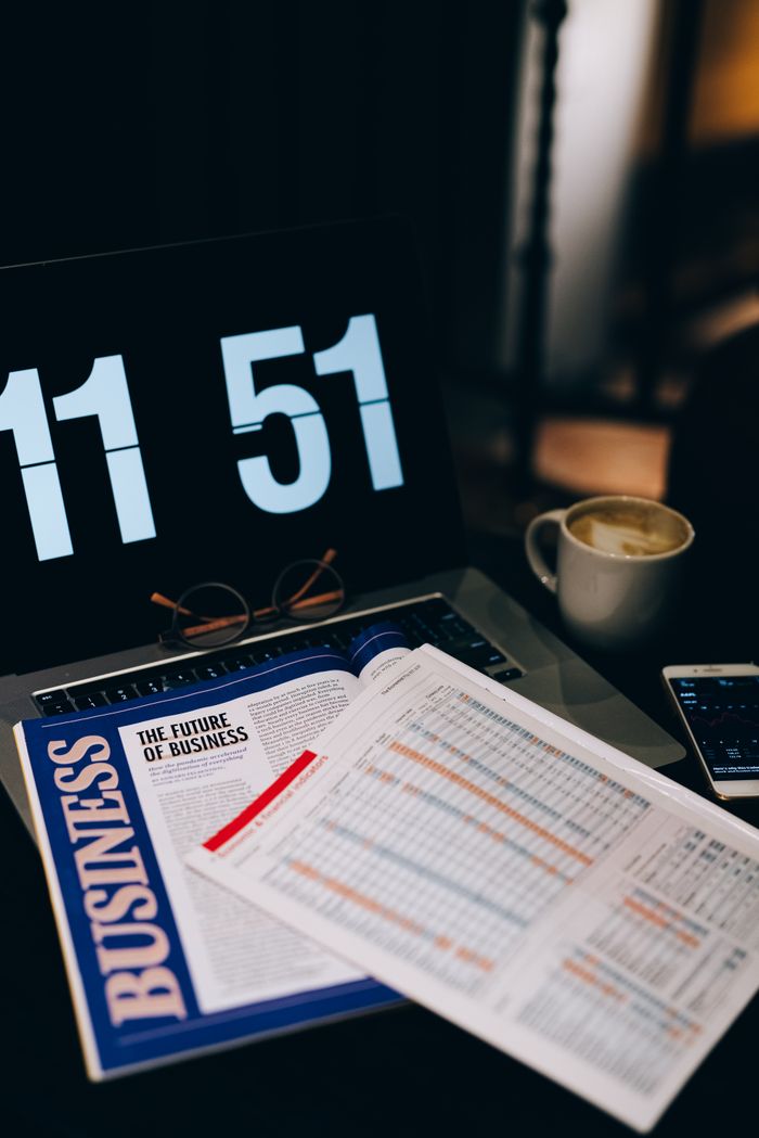 A workspace featuring business analytics documents, laptop, and coffee, symbolizing productivity and analysis.